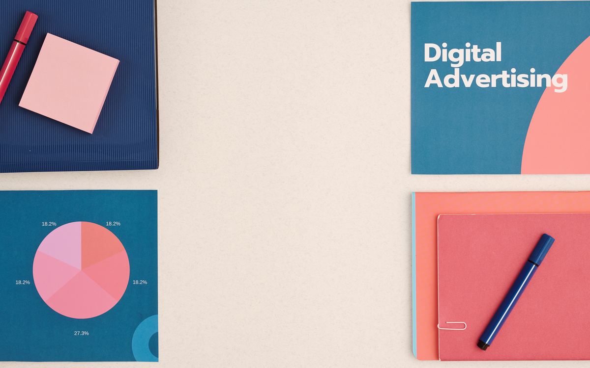 Cuaderno y tarjetas de publicidad digital con una gráfica circular sobre una mesa