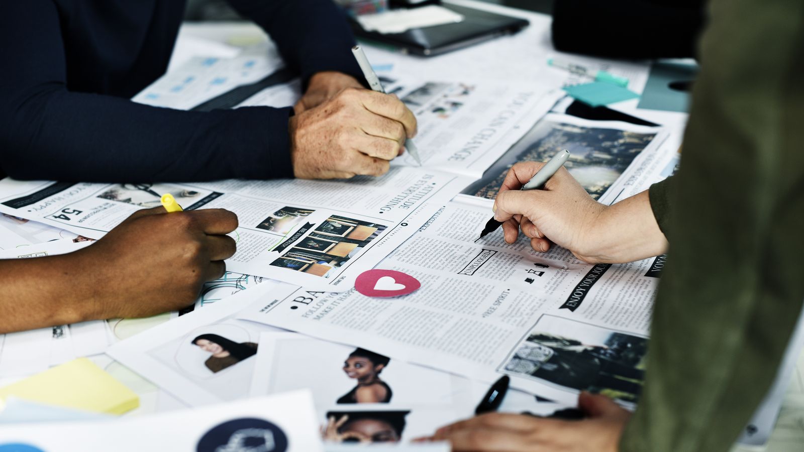 Manos de un equipo revisando impresos y notas creativas sobre una mesa de trabajo