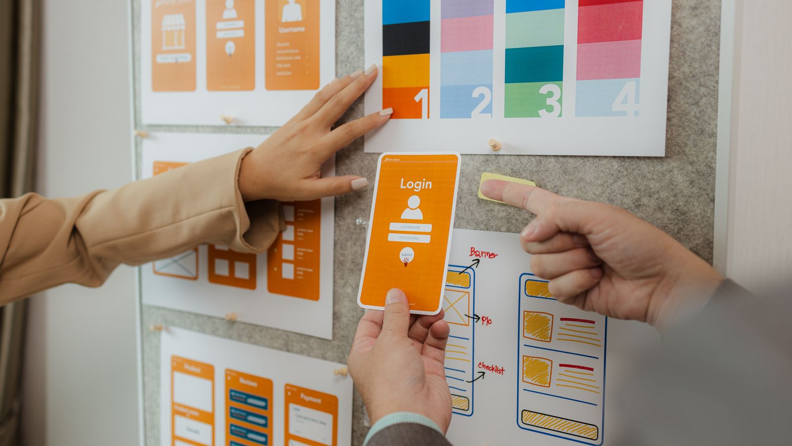 Manos de un equipo de desarrollo organizando tarjetas de flujo de pantallas en una pared