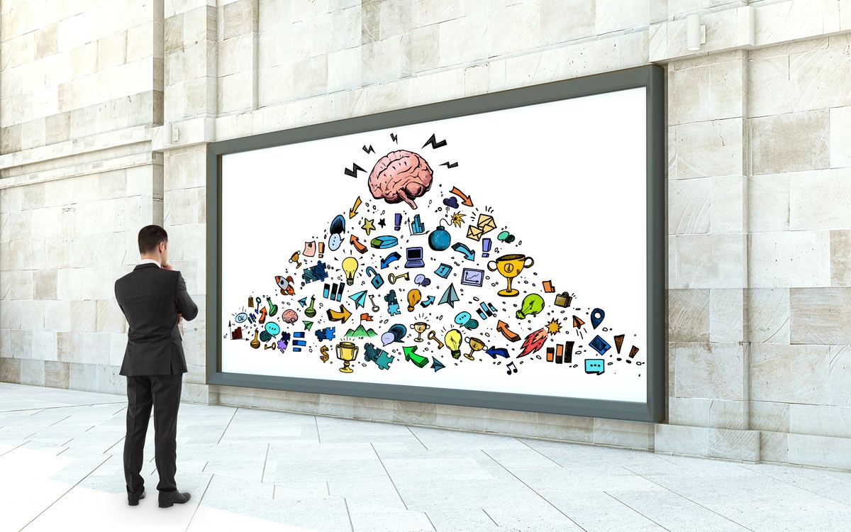 Persona de traje frente a una gran pantalla con un cerebro rodeado de íconos de marketing