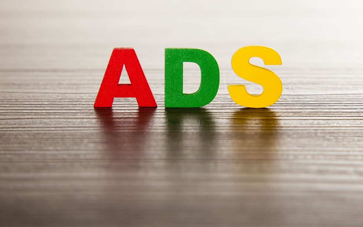 Letras de colores que forman la palabra ADS sobre una mesa de madera
