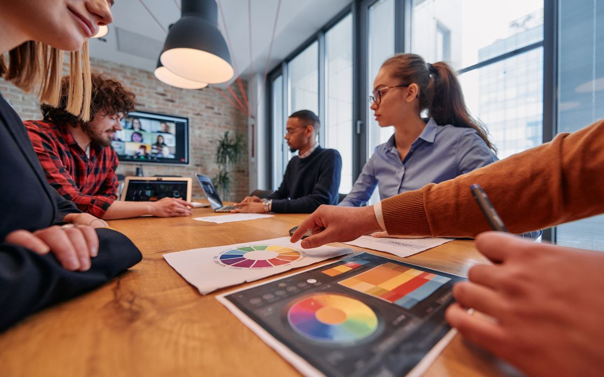 Equipo revisando paletas de color y piezas creativas sobre una mesa de trabajo